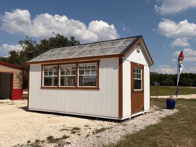A small white shed with brown trim under a blue sky.