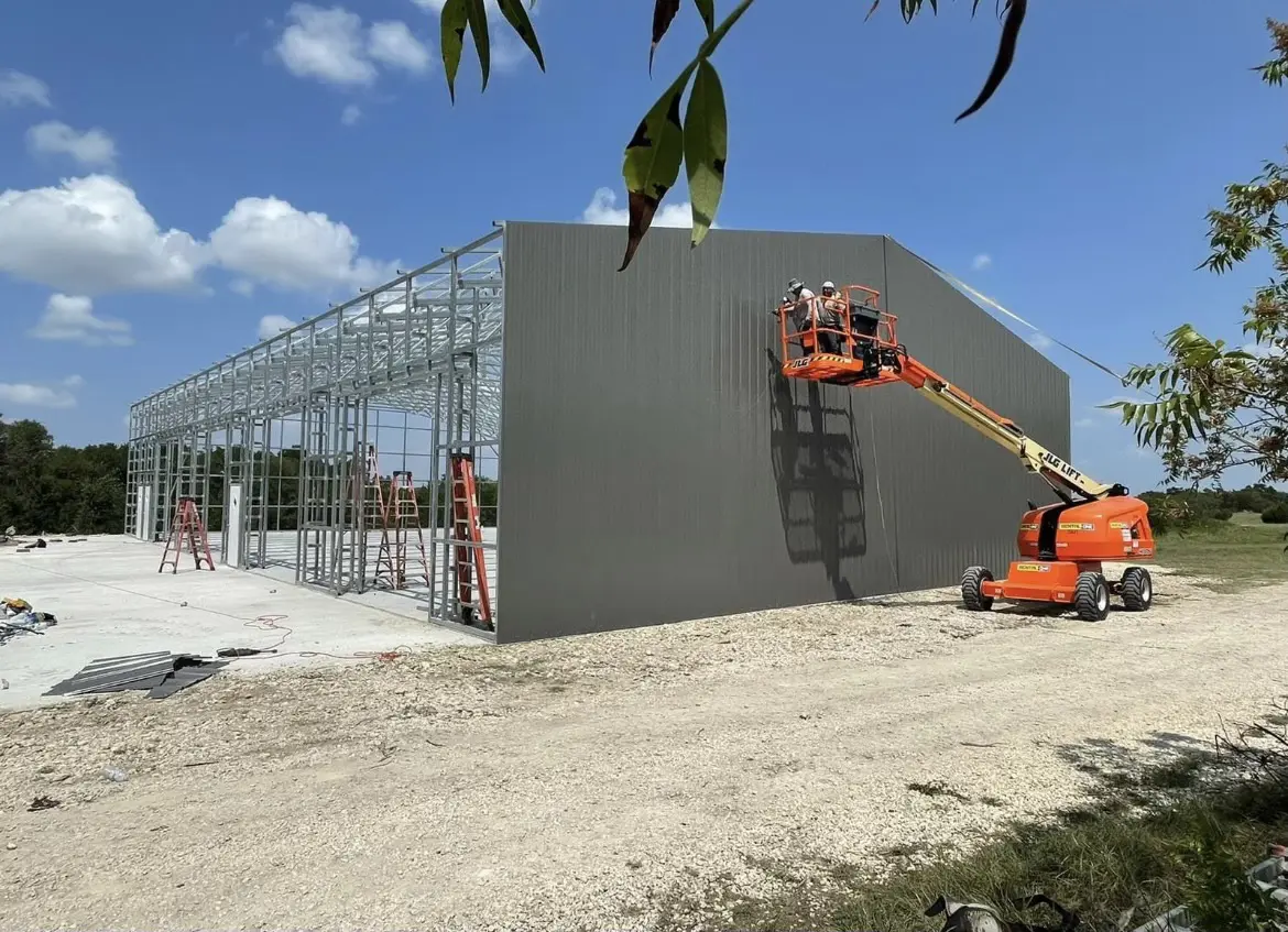 Workers applying exterior wall finish on a construction site with a boom lift.
